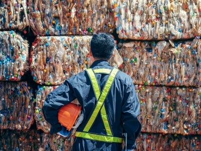 Person standing in front of stacks of plastic organized for recycling