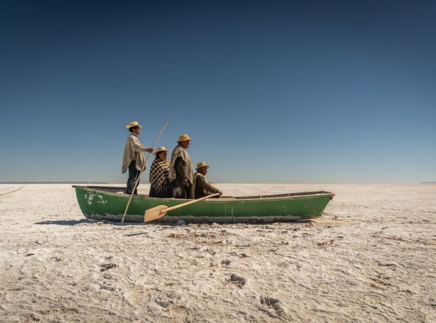 Artistic representation of Indigenous Bolivians in a boat on dried up Lake Poopo
