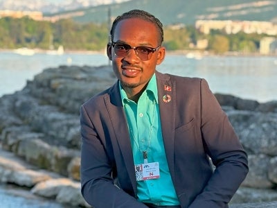 Man sitting by water with hills in background