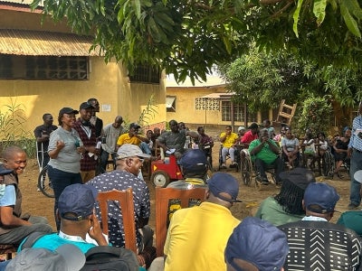 Group of people in a circle listening to speakers outside