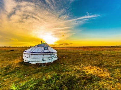Yurt in the Mongolian steppe with sun and colorful sky